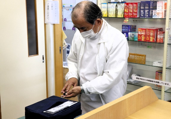指紋認証鍵により施錠された医薬品が入った専用箱を解錠するまつおか薬局松岡政臣代表取締役